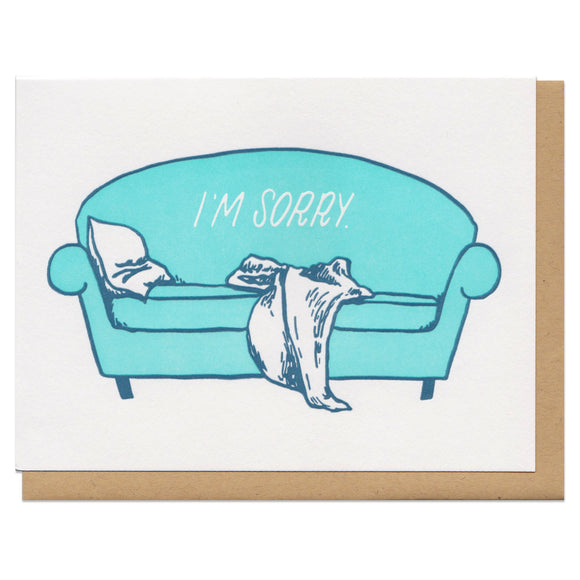 white greeting card featuring an illustrated teal couch with a pillow and blanket slumped on it. white text on the couch reads 