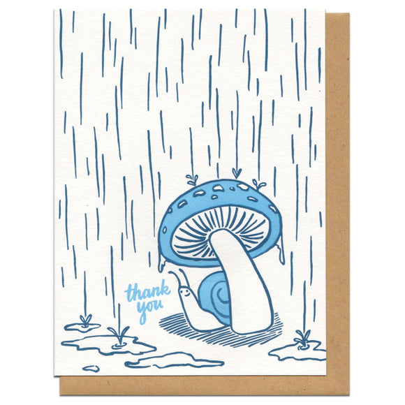 white greeting card witn an illustration of a snail hiding from the rain beneath a mushroom next to hand-lettering that reads 