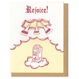 white greeting card featuring a maroon and yellow illustration of a carton of eggnog ascending twards trumpets in the clouds. hand lettering at the top reads "rejoice!"