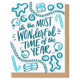 A greeting card and envelope featuring cookies, ornaments, and garland with text in the center that says "it's the most wonderful time of the year."