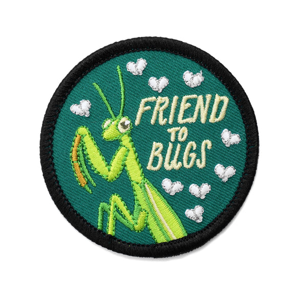 An iron on embroidered circle patch with a black outline and a forest green background with a praying mantis, flies, and text that reads 