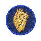 An round embroidered patch with an iron on back featuring a golden anatomical heart with a navy blue background.