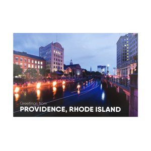 postcard photograph of Waterfire occuring on the Providence canal at dusk. white text on the bottom reads "greetings from providence, rhode island"