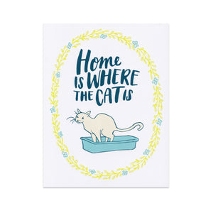 An art print of a cat squatting in a little box with flowers around him and text that reads "home is where the cat is."