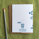 Greeting card with kraft envelope. Reads "happy birthday" in hand-written, serif font, surrounded by illustrated fish of various sizes and shapes. Shades of blue.