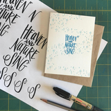 A greeting card and envelope featuring stars and dots in a swirling pattern with hand lettered script in the center that reads "heaven and nature sing"