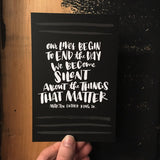 black postcard featuring a hand-lettered quote "Our lives begin to end the day we become silent about things that matter. Martin Luther King JR." photographed hand-held in front of a wall