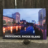 postcard photograph of Waterfire occuring on the Providence canal at dusk. white text on the bottom reads "greetings from providence, rhode island"