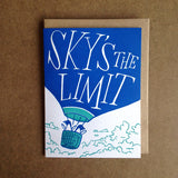 white greeting card featuring an illustration of two penguins riding in a hot air balloon. hand-lettering on the balloon reads "sky's the limit"