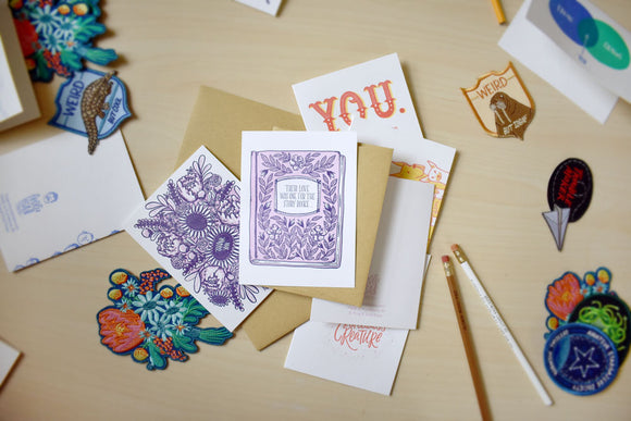 Three letterpressed greeting cards are sitting on top of each other, the top one features a story book wedding card and below it is a card with a thank you bouquet on it.