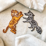 tuff tiger and tuff wolf patch photographed together on a grey sweatshirt