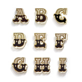 Letters A-I enamel pins with butterfly backer delicately handlettered in black, white, and gold.