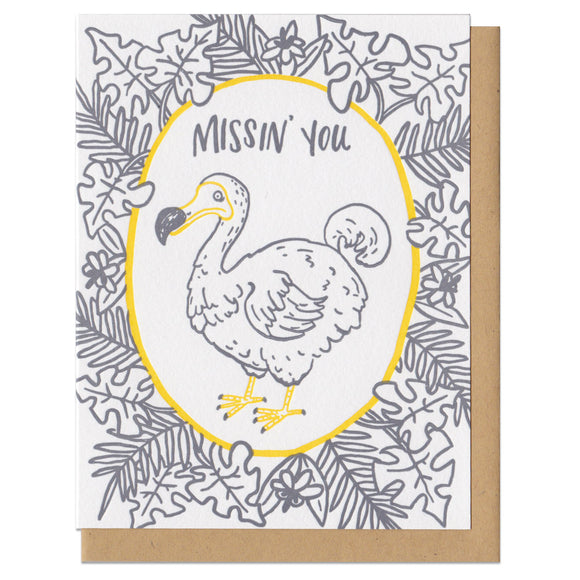 Greeeting card and kraft paper envelope. Grey, illustrated tropical leaves surrounding dodo bird with text above him that reads, 