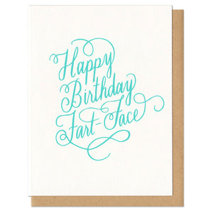 Greeting card and kraft paper envelope. Text reads "happy birthday fart face" in ornate, script, hand-drawn, mint colored letters.