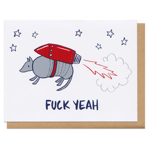 Greeting card and kraft paper envelope. Illustration of armadillo wearing a jet pack, surrounded by stars. Text below reads, "fuck yeah."