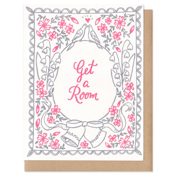 A greeting card with an envelope featuring grey and pink flowers, wedding bells, and kissing birds on top of a circle with script inside that says, 