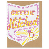 A greeting card with an envelope die-cut in the shape of badge with a Vegas style sign with text inside saying "gettin hitched" pointing at a ring. wedding, greeting card, cards, stationery, engagement