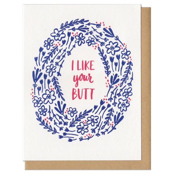 Greeting card and kraft paper envelope. Illustrated wreath of navy flowers surround red/pink text that reads, 
