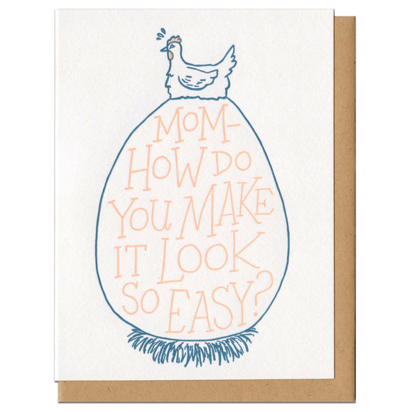 white greeting card featuring a blue illustration of a hen sitting atop an extremely large egg. orange hand-lettering on the egg reads 