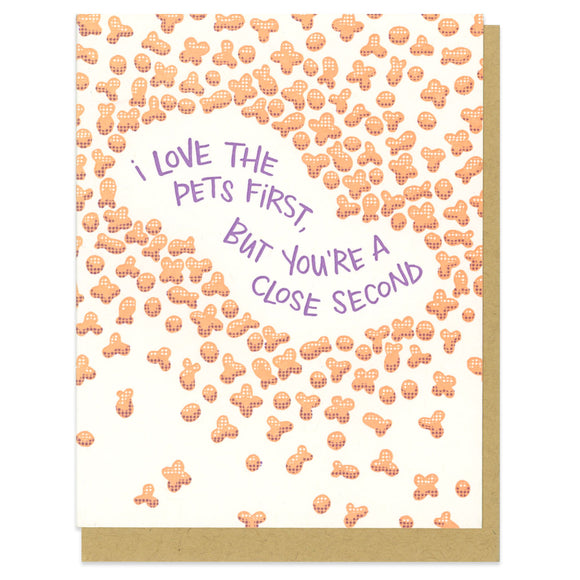 A greeting card and envelope featuring cat and dog kibble in orange with purple text in the middle that says 