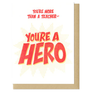white greeting card with red text which reads "you're more than a teacher - you're a hero"