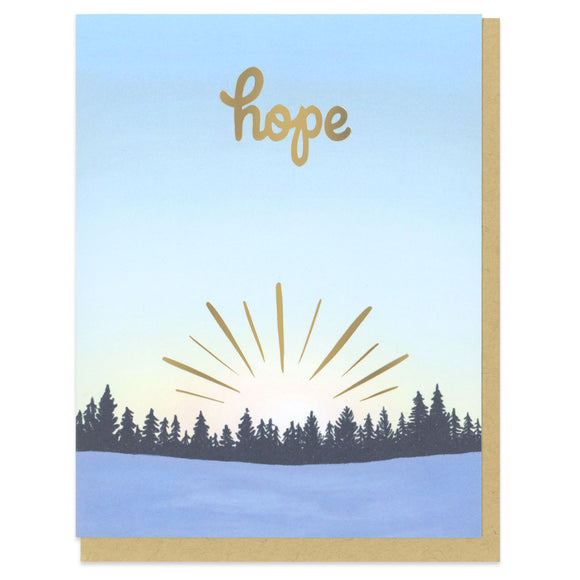 A greeting card and envelope printed in full color with a view of a tree line at sunrise with gold foil sunrays and the word 