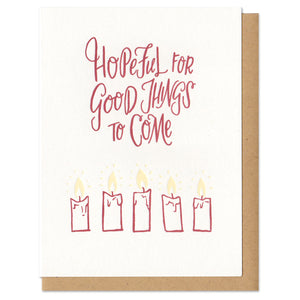 A greeting card and envelope featuring 5 partially burned lit candles with text that says "hopeful for good things to come."