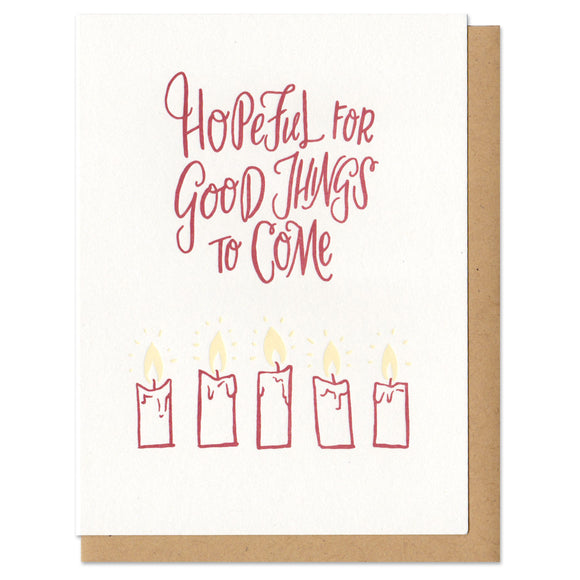 A greeting card and envelope featuring 5 partially burned lit candles with text that says 