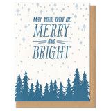 white greeting card with a navy pine tree design beneath hand-lettering that reads "may your days be merry and bright" amongst a pale blue starry sky