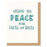 white greeting card with teal handlettering which reads "wishing you peace in the hustle and bustle"