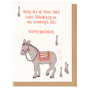 A greeting card and envelope featuring a tail-less donkey with 5 tails nearby ready to be pinned. He's a little nervous and the text reads, "may all of your tails land squarely on the donkey's ass. Happy birthday." stationery, greeting card, cards, birthday card, donkey, funny