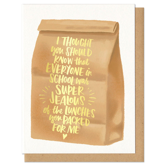 Greeting card and kraft paper envelope. Illustration of brown paper bag with text on it in gold foil that reads, 