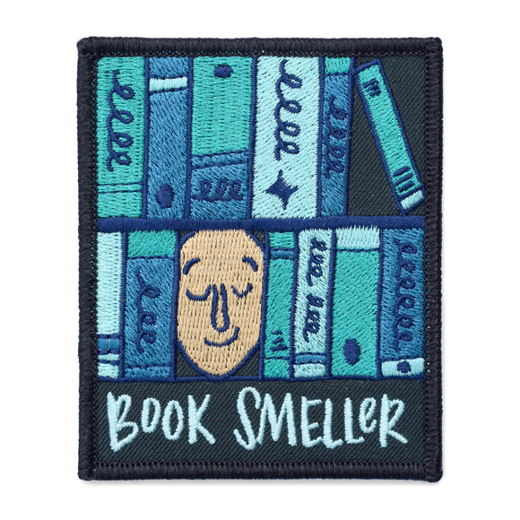 A rectangle patch with a face surrounded by various shades of blue books with text under it that says, 