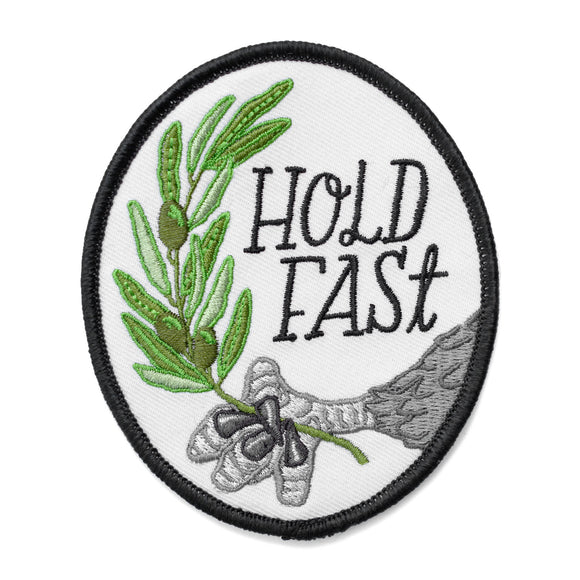 An oval iron on embroidered patch featuring an eagle's claw holding an olive branch with script text next to it that says, 