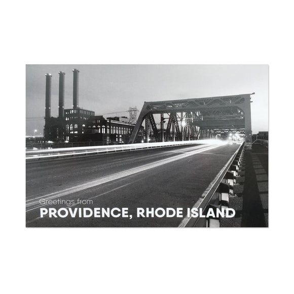 black and white postcard photograph of night-time traffic driving over a downtown providence bridge with the iconic power station smoke stacks visable in the background. white text on the bottom reads 