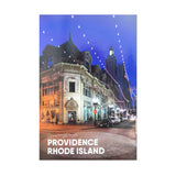 postcard photograph of iconic downtown Westminster Street lit up at night with white text on the bottom that reads "Providence, Rhod Island"