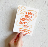 Greeting card and kraft paper envelope. Illustration of vintage Pyrex casserole dish with handlettered type in the steam that reads "I'd like to make a casserole with you, If you know what I mean." In shades of orange.