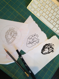 Original illustrations of the heart of gold patch on a work bench.