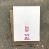 backside of the greeting card which shows a small yellow flower and pink text that reads "Frog & Toad Press, Made in Provience, RI"