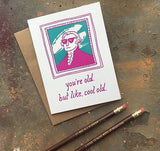 greeting card with a pink and teal illustration of Gilbert Stuart which reads "you're old, but like, cool old" shown with pencils