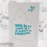 white greeting card with an illstration of an aeroplane flying through a cloud, teal hand-lettering on the cloud reads "thank you for driving me to the airport at an ungodly hour" photographed with design sketches